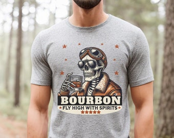 May include: Gray t-shirt with a skeleton wearing aviator goggles and a leather jacket holding a glass of bourbon. The text on the shirt reads "Bourbon Fly High With Spirits".