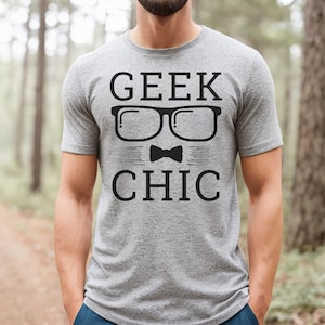 May include: A gray t-shirt with the text "GEEK CHIC" in black. The text is surrounded by a graphic of a pair of glasses and a bow tie.