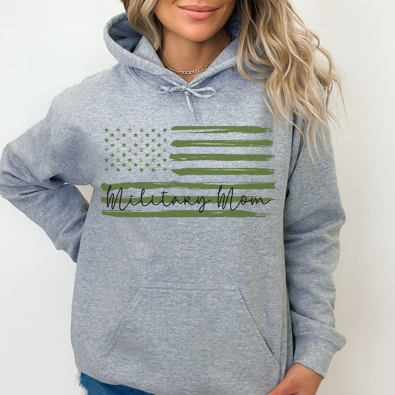 May include: Gray hooded sweatshirt with a green and white American flag design and the text "Military Mom" in black.
