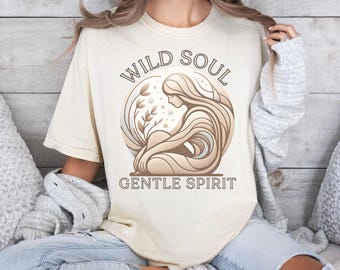 May include: A beige t-shirt with a graphic design of a woman with flowing hair and the text "WILD SOUL GENTLE SPIRIT".