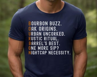 May include: A navy blue t-shirt with white text that reads "BOURBON BUZZ. OAK ORIGINS. URBAN UNCORKED. RUSTIC RITUAL. BARREL'S BEST. ONE MORE SIP? NIGHTCAP NECESSITY."