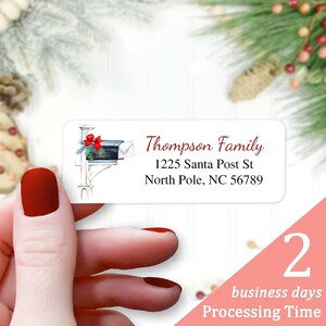 May include: White return address label with a watercolor illustration of a red mailbox with a green wreath and a red bow. The text on the label reads "Thompson Family, 1225 Santa Post St, North Pole, NC 56789".