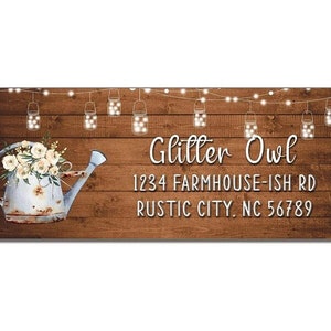 May include: A rustic wooden sign with a white watering can filled with white flowers. The sign has string lights with mason jars hanging from them. The text on the sign reads "Glitter Owl 1234 Farmhouse-ish Rd Rustic City, NC 56789".