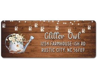 May include: A rustic wooden sign with a white watering can filled with white flowers. The sign has string lights with mason jars hanging from them. The text on the sign reads "Glitter Owl 1234 Farmhouse-ish Rd Rustic City, NC 56789".
