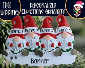 Op de afbeelding: Gepersonaliseerde kerstversiering met vier kerstmannetjes met rode mutsen, witte baarden en sneeuwvlokken in hun handen. De kerstmannetjes zitten op een wit banner met de tekst "Naam 1", "Naam 2", "Naam 3", "Naam 4", "jaar" en "Banner".