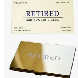 May include: A business card and a gold-colored card holder. The business card is cream-colored with the word "RETIRED" in navy blue, along with other text. The card holder has the word "RETIRED" in silver.