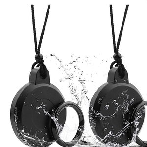 May include: Two black lens caps with a black cord attached. The lens caps are in a pool of water with water splashing around them.