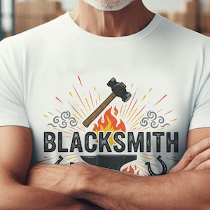 May include: White t-shirt featuring a blacksmith design. The graphic includes a hammer, anvil, horseshoe, and the word "BLACKSMITH" in bold letters. The design is set against a backdrop of red and yellow flames and decorative swirls.