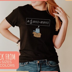 May include: Black t-shirt with a white graphic of a cat in a box and the text "iħ d/dt |ψ(t)>=H|ψ(t)".