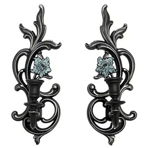 May include: A pair of black metal wall sconces with ornate floral designs and blue floral accents. Each sconce has a single candle holder.