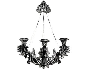 Op de afbeelding: Een versierde metalen kandelaar in zwart en zilver met drie kaarshouders en een decoratief bovenstuk. De kandelaar hangt aan kettingen.