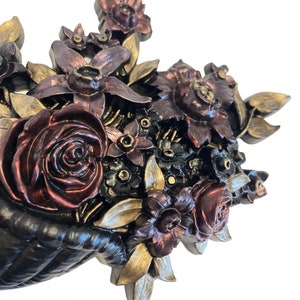 Puede incluir: Una decoraci&oacute;n de pared que representa una cesta desbordante de flores esculpidas en tonos burdeos, dorado y negro. Las flores est&aacute;n dispuestas en un estilo realista, con detalles y texturas intrincadas.