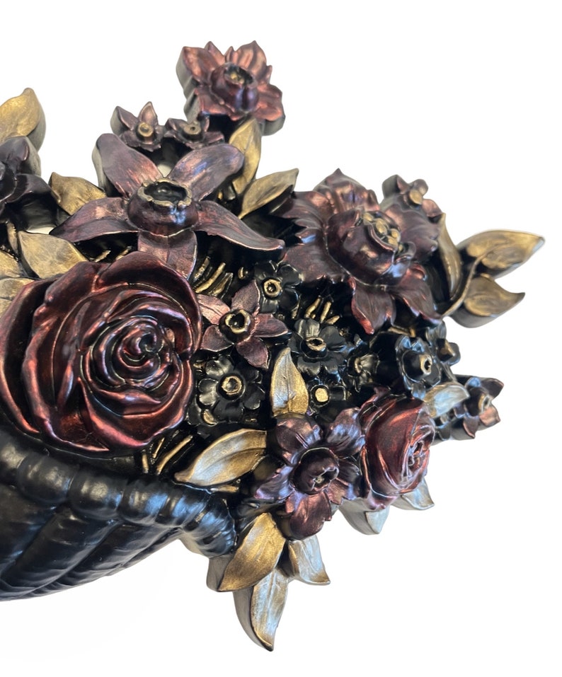 Puede incluir: Una decoraci&oacute;n de pared que representa una cesta desbordante de flores esculpidas en tonos burdeos, dorado y negro. Las flores est&aacute;n dispuestas en un estilo realista, con detalles y texturas intrincadas.