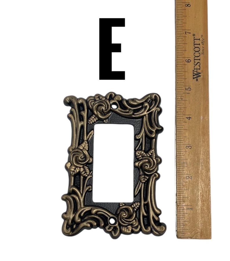 May include: A black and gold decorative light switch cover with a floral design. The cover is approximately 4 inches tall and 3 inches wide.