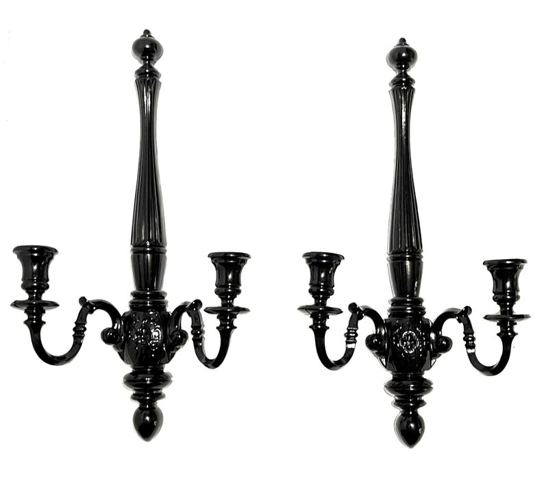 Op de afbeelding: Een paar zwarte metalen wandkandelaars met elk drie kaarsarmen. De kandelaars hebben een decoratief, versierd ontwerp.