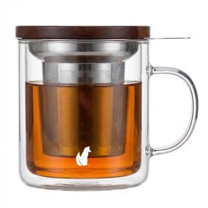 May include: A clear glass tea mug with a stainless steel infuser and a dark wood lid. The mug contains brewed tea, and a white fox logo is visible on the glass. The handle is clear glass.