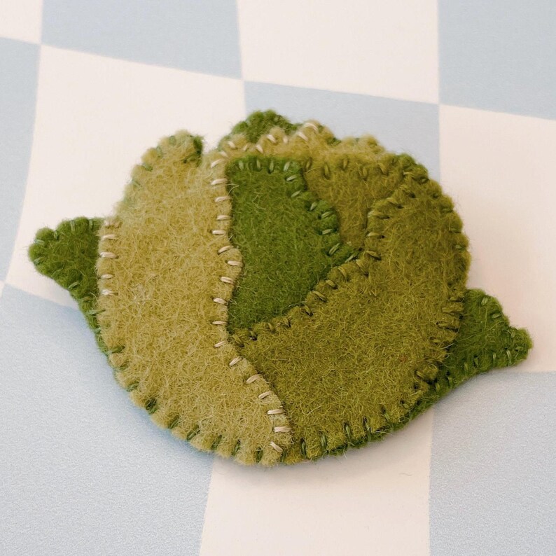 May include: A felt green and brown cabbage with a stitched edge.