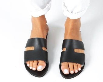 May include: A pair of black leather sandals with a double strap design. The sandals have a simple, minimalist style and are perfect for summer.