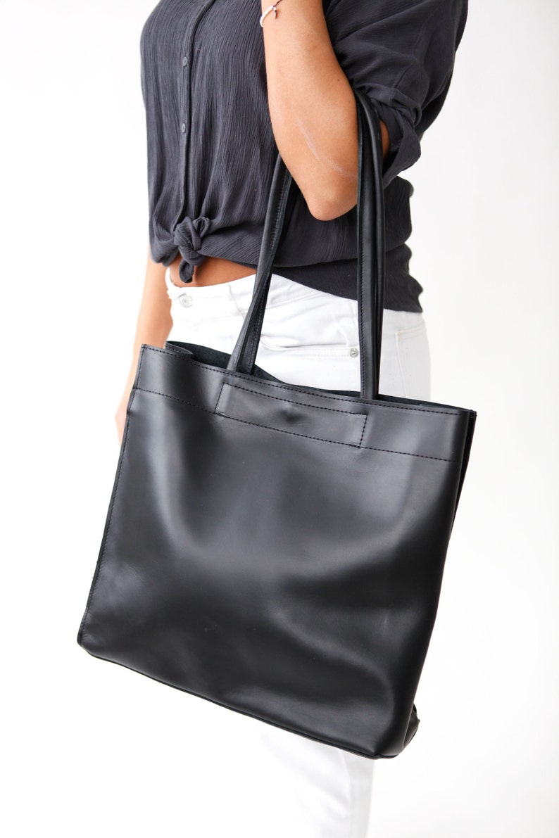 May include: A black leather tote bag with a top handle and a wide, rectangular shape.