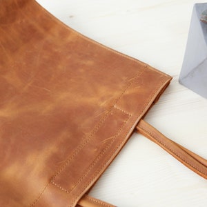 May include: A brown leather tote bag with two straps. The bag has a worn, distressed look.