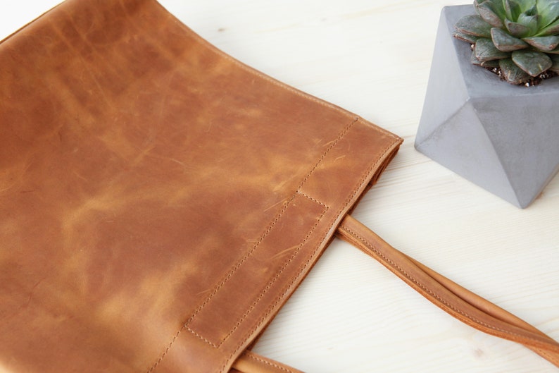 May include: A brown leather tote bag with two straps. The bag has a worn, distressed look.