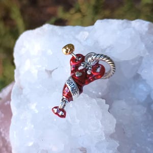 K&ouml;nnte beinhalten: Ein roter und silberner Hummer-Anh&auml;nger mit dem Wort "MAINE" darauf. Der Anh&auml;nger hat einen goldfarbenen Akzent und einen silberfarbenen, gedrehten Ring.