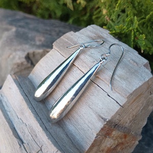 May include: A pair of silver teardrop-shaped earrings with a smooth, polished finish.