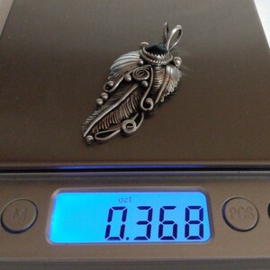 Puede incluir: Un colgante de plata en forma de pluma con una piedra negra y detalles intrincados, que pesa 0,368 onzas.