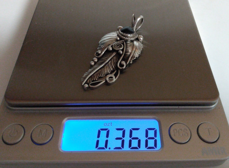 Puede incluir: Un colgante de plata en forma de pluma con una piedra negra y detalles intrincados, que pesa 0,368 onzas.