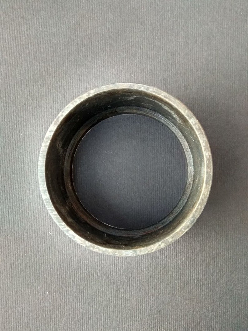 May include: A dark gray metal ring with a smooth, circular surface. The ring is about 2 inches in diameter.
