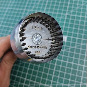 May include: A silver metal tool with 4mm diameter holes for making petri dishes. The tool is 1.5 inches in diameter and has the text "Handmade Petri" engraved on it.