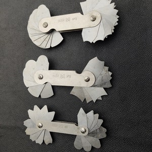 Peut inclure: Trois jauges d'angle en métal argenté avec un design en forme d'éventail. Chaque jauge a une poignée avec le texte "CCCP" et un numéro. Les numéros sont "№3", "№2" et "№1".