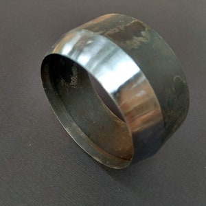 May include: A metal ring-shaped tool with a smooth, polished edge and a rough, textured surface. The tool is used for punching holes in leather or other materials.