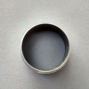 May include: A silver-colored metal ring with a smooth, rounded surface.
