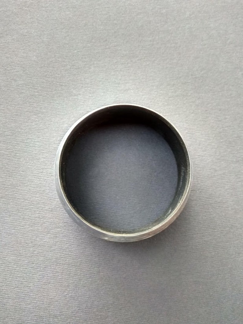 May include: A silver-colored metal ring with a smooth, rounded surface.