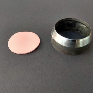 Op de afbeelding: Een lederponsgereedschap en een roze lederen cirkel die met het gereedschap is uitgesneden.