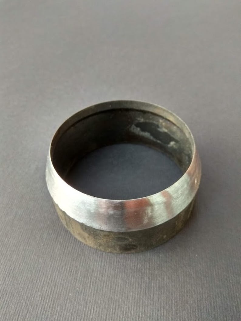 May include: A silver metal ring with a dark gray band. The ring is smooth and shiny.