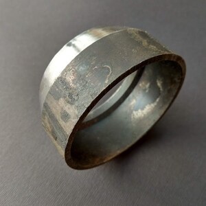 May include: A silver and black metal ring with a smooth, polished surface. The ring is made of two pieces of metal that are joined together.