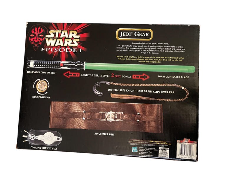 May include: Star Wars Episode I Jedi Gear playset with a green lightsaber, a brown belt with metal buckles, and a hair braid clip. The box features the text "Lightsaber is over 2 feet long!"