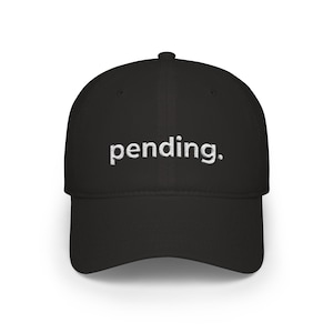 Könnte beinhalten: Schwarze Baseballkappe mit dem Wort "pending" in Weiß auf der Vorderseite gestickt. Die Kappe hat einen gebogenen Schirm und ein strukturiertes Design. Ein lässiges Accessoire für den Alltag.