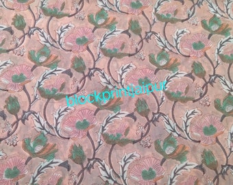 May include: A pink and green floral fabric with a repeating pattern of flowers and leaves. The fabric has a light brown background and the text "blockprintjaipur" is printed in blue on the fabric.