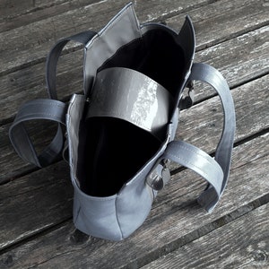 May include: A gray tote bag with two handles. The bag is open and the inside is empty.