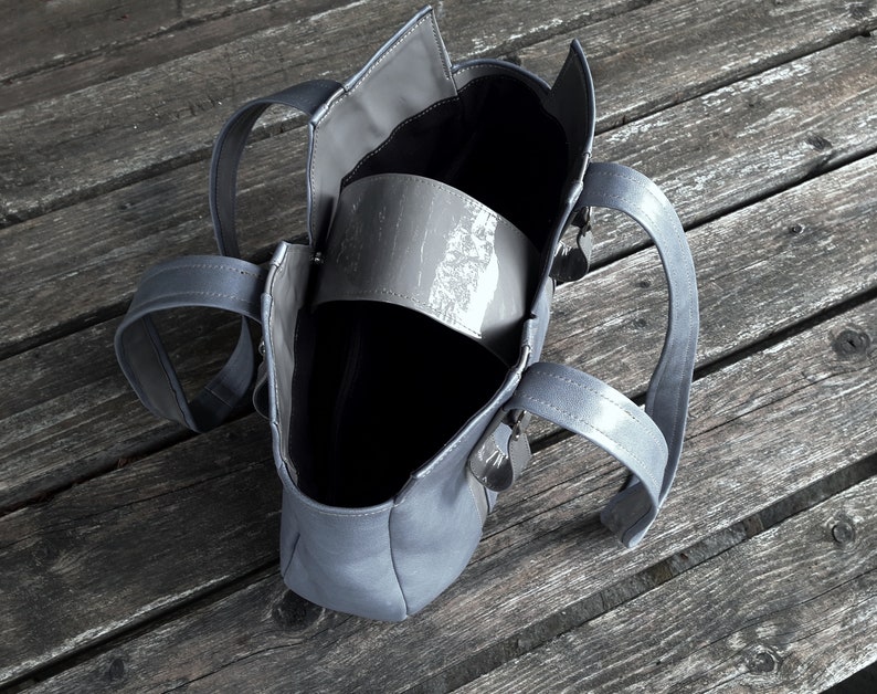 May include: A gray tote bag with two handles. The bag is open and the inside is empty.