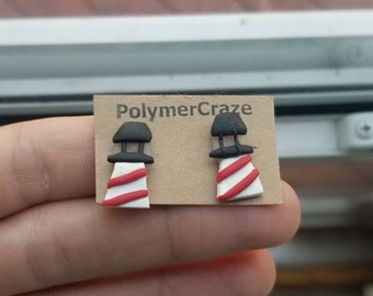 May include: A pair of red and white striped lighthouse earrings with black tops. The earrings are on a card that says "PolymerCraze".