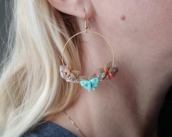 May include: Gold hoop earrings with three polymer clay butterfly charms. The butterflies are brown, orange, and turquoise.