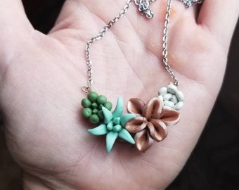 May include: A silver chain necklace with a cluster of three polymer clay succulents. The succulents are green, teal, and copper.