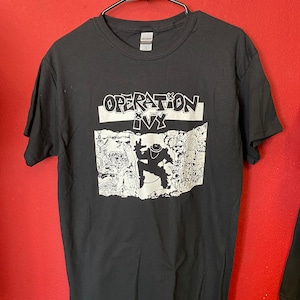 May include: Black t-shirt with a white graphic print of a person in a hat and the text "OPERATION IVY".