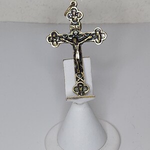 Op de afbeelding: Een gouden kruis hanger met ingewikkelde details. Het kruis toont een figuur van Jezus Christus met de inscriptie "INRI" boven zijn hoofd. De hanger wordt getoond op een witte standaard.