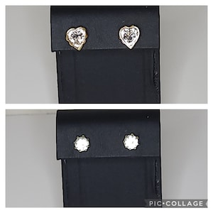 May include: Two pairs of earrings on a black display card. One pair is heart-shaped with clear stones, the other pair is round with clear stones.