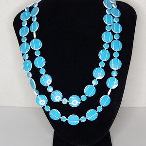 May include: A turquoise and white beaded necklace with large round beads. The beads have a white stripe pattern.